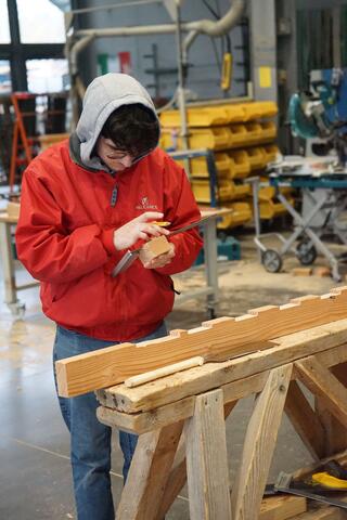 étudiant qui mesure un morceau de bois